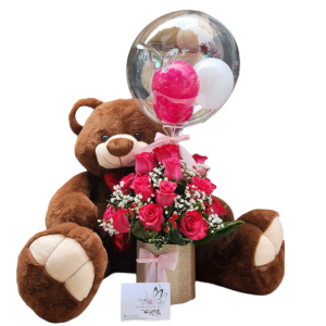 Cilindro floral con 24 rosas fucsias, follaje perla, cafeto, globo burbuja personalizado y peluche de 70 cm