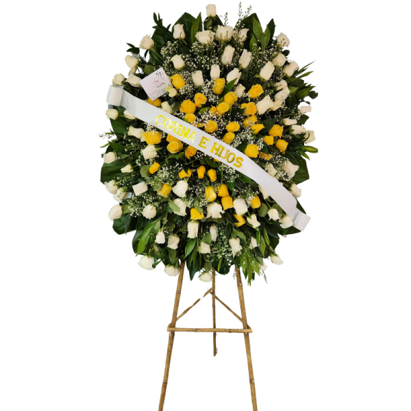 Corona fúnebre con rosas blancas y amarillas, follaje verde y detalles en perlas.