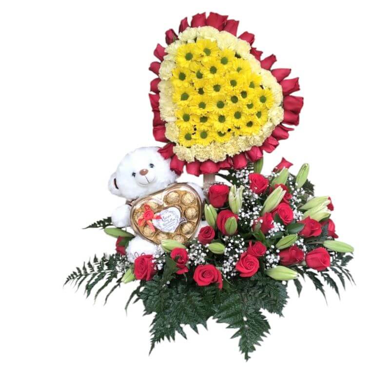 Arreglo en forma de corazón con 60 rosas rojas, margaritas amarillas, lirios blancos, follaje y peluche con chocolates Ferrero